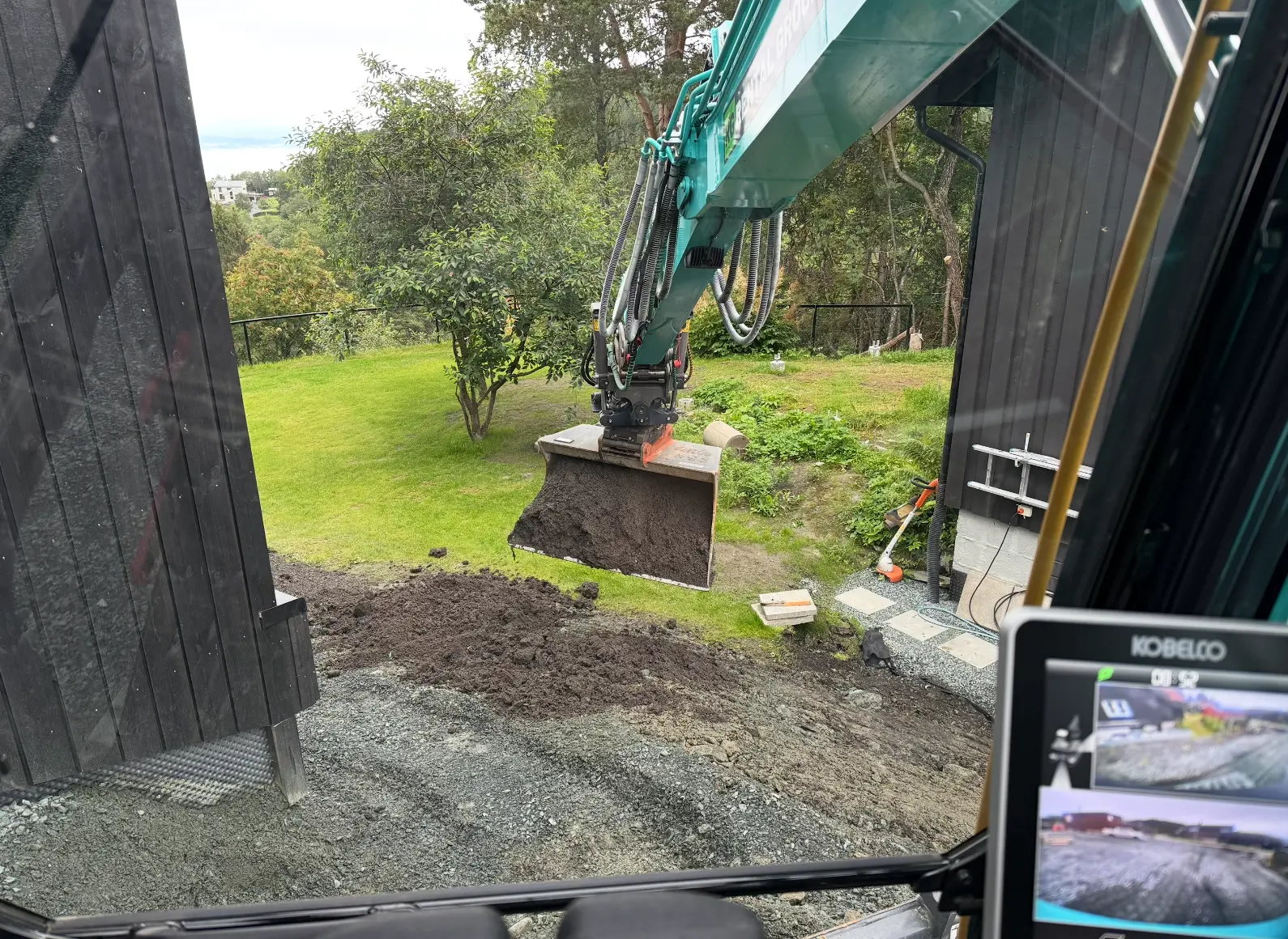 Gravemaskin i arbeid med opparbeiding av hage