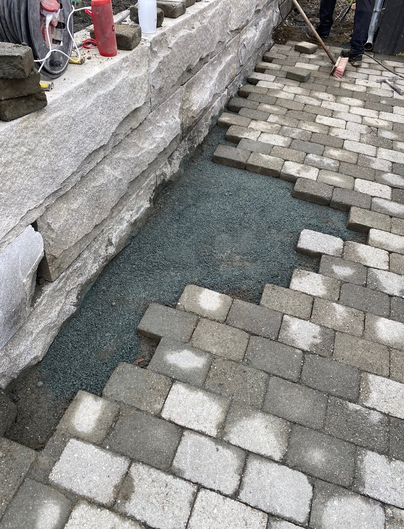Legging av belegningsstein langs natursteinsmur